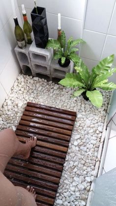 a person is standing on a mat in the middle of a room with rocks and plants