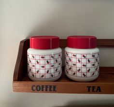 two coffee cups sitting on top of a wooden shelf