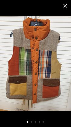 an orange vest hanging on a door with some buttons in the front and side pockets