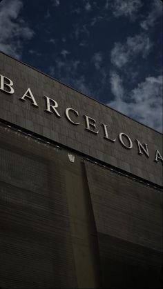 the sign for barcelona on top of a building under a blue sky with white clouds