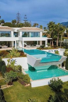 an aerial view of a house with a pool in the middle and palm trees surrounding it