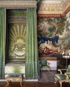 an ornate bedroom with green curtains and paintings on the walls, along with antique furniture