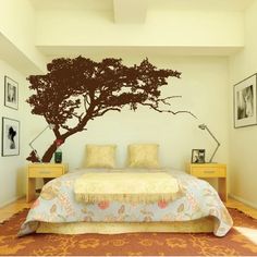 a bedroom with a large tree painted on the wall and bed in front of it