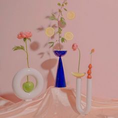 three vases with flowers in them on a pink table cloth next to each other