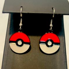 pair of earrings with red and white pokemon pokeball design on black earwires