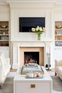 a living room with white furniture and a fire place in the middle of the room