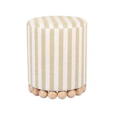 a striped ottoman with wooden beads on the top and bottom, sitting in front of a white background