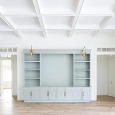 an empty living room with white walls and wooden flooring, built in shelving unit