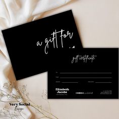 two black and white business cards sitting on top of each other next to some flowers