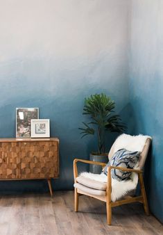 a living room with blue walls and wooden furniture in the corner, along with a potted plant