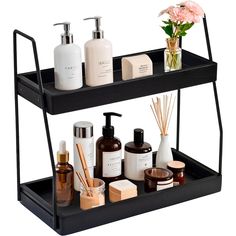 two tiered shelf with soaps, lotion bottles and candles on it next to a pink flower