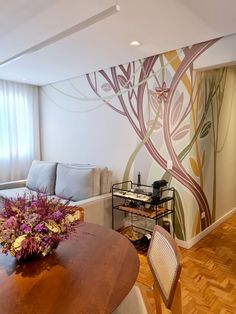 a living room filled with furniture next to a wooden table and wall painting on the walls