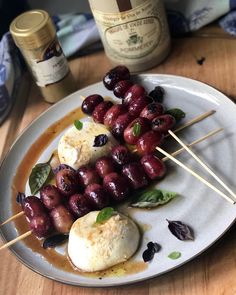 a plate topped with meat and veggies on skewers next to a bottle of wine