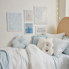 a bed with pillows and pictures on the wall above it, along with a teddy bear