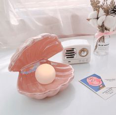 an egg shell shaped alarm clock sitting on top of a table next to a vase with flowers