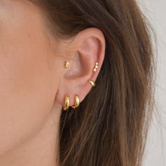 a close up of a person's ear with two small gold earrings on it