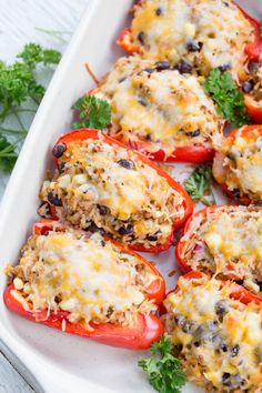 stuffed bell peppers with cheese and black olives in a white casserole dish