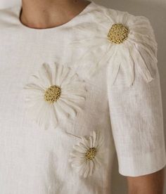 a woman wearing a white dress with flowers on the front and back of her shirt