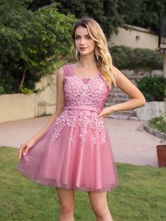 a woman in a short pink dress posing for the camera with her hand on her hip