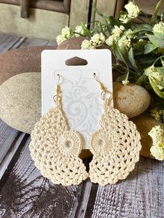 the crocheted earrings are on display next to some flowers