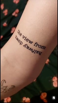 a person with a tattoo on their arm that reads we view from afar, and the words are written in cursive font