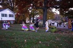 several children are walking down the street in colorful dresses and holding hands with each other