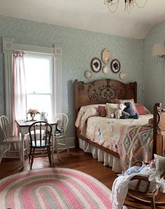 a bedroom with a bed, rocking chair and table in it's center area