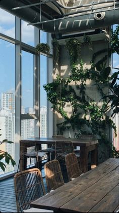 an indoor dining area with wooden table and wicker chairs in front of large windows