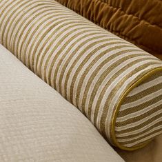 two pillows sitting next to each other on top of a bed covered in white and brown sheets