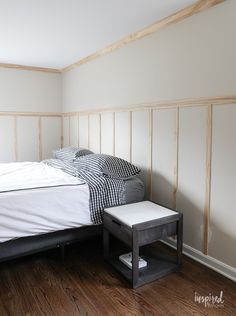 a bed sitting on top of a hard wood floor next to a white wall under construction