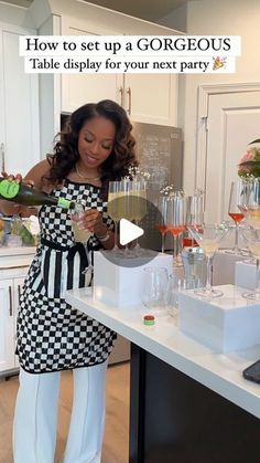 a woman standing in front of a counter filled with wine glasses