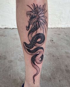 a black and white tattoo on the leg of a person with a dragon in it