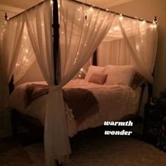 a bed with white curtains and lights on it