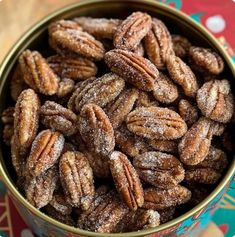 a bowl full of sugared pecans sitting on top of a colorful table cloth