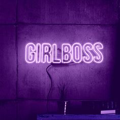 a purple neon sign that says girlboss on the wall next to a potted plant