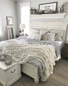 a white bed sitting in a bedroom next to a window with lots of pillows and blankets on top of it