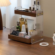 a wooden table topped with lots of cosmetics and personal care items next to a lamp