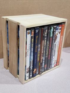 a wooden box with several dvd's in it sitting on a table next to a wall