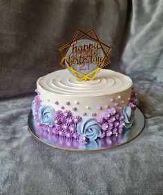 a birthday cake with purple flowers and a happy birthday sign on top that says happy birthday