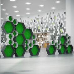 a room with green and white hexagonal structures on the wall, in front of a dining area