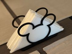 a mickey mouse napkin holder on top of a table with white and black napkins