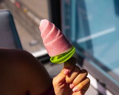 a woman holding up a pink and green ice cream cone