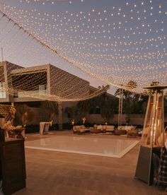 an outdoor party with lights strung over the dance floor and tables set up in front of it