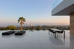 a table and chairs on a white tiled floor with palm trees in the background at sunset