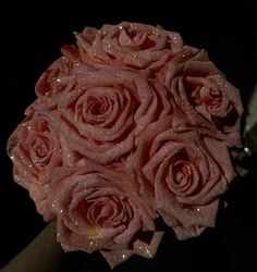 a bouquet of pink roses with water droplets on them sitting on a black table top