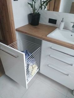 a white sink sitting under a bathroom mirror next to a wooden counter with a plant in it