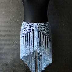 a crocheted skirt with tassels is displayed on a mannequin