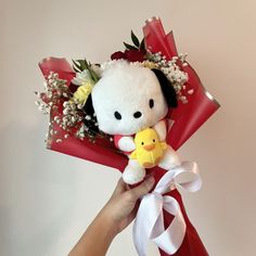 a person holding a stuffed animal with flowers in it's hair and wrapped in red ribbon