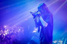 a man with long hair holding a microphone in front of a crowd at a concert