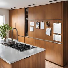 a modern kitchen with wooden cabinets and white counter tops, along with a stainless steel stove top